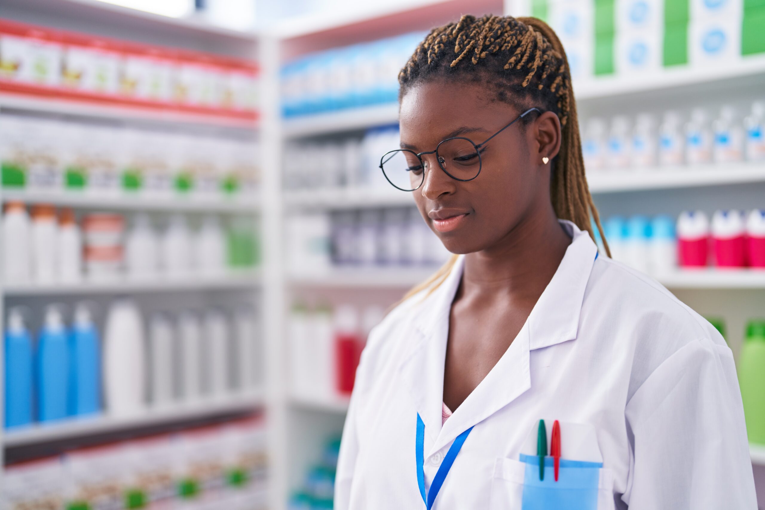 African american woman pharmacist standing with serious expression at pharmacy